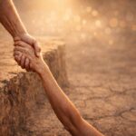 Hand reaching down to pull someone up from the edge, symbolizing God’s rescuing love